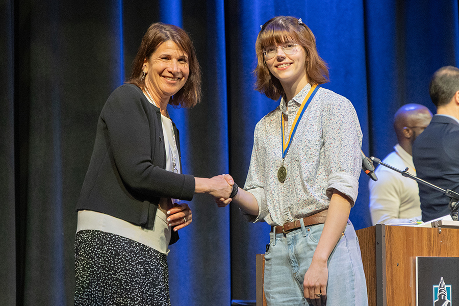 Two women shake hands on stage.