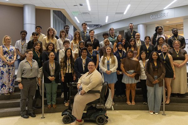 A large group of students wearing Phi Theta Kappa medallions stand on a stairwell for a photograph.