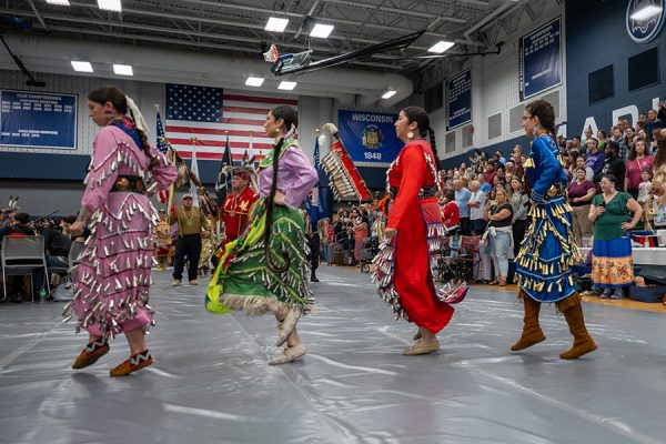 Four women in brightly colored traditional dress dance at the Madison College Pow Wow.